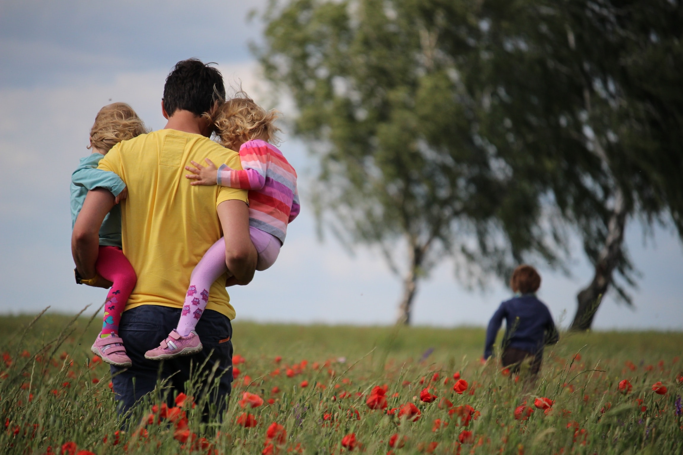 dad-holding-two-kids-field